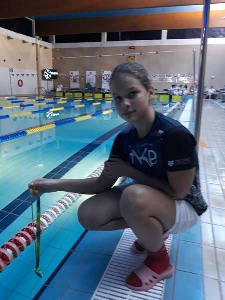 Karolina Klajmon z medalem na tle basenu